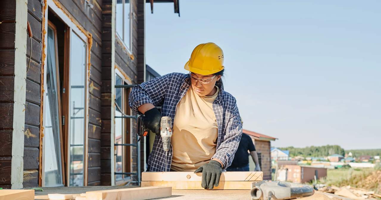 Construction crew member drilling lumber at a job site